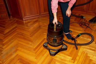 A middle-aged woman collects a vacuum cleaner for house cleaning.