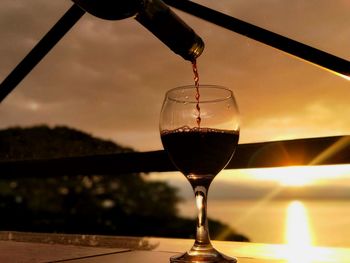 Close-up of wineglass on table during sunset