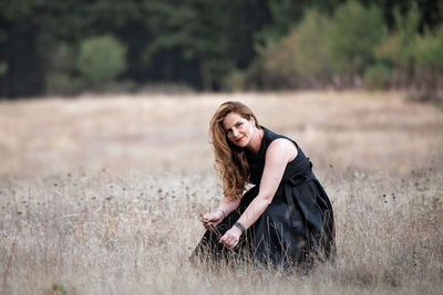 Young woman with arms raised on field