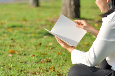 Midsection of woman holding umbrella on field