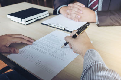 Close-up of businessmen doing paperwork at desk in office