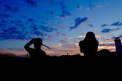 Silhouette friends against sky during sunset