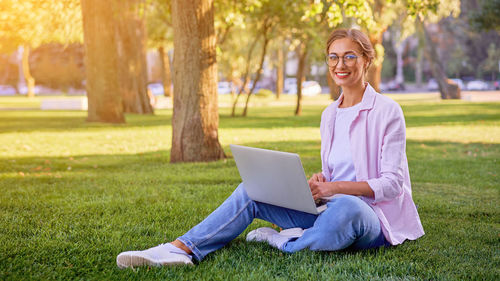 Woman using phone while sitting on grass