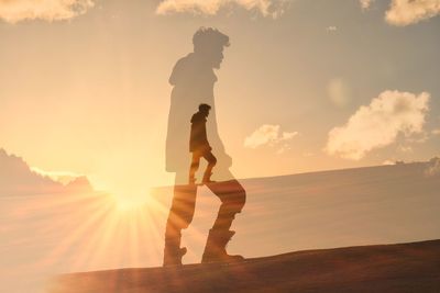 Low angle view of man standing on field against sky during sunset