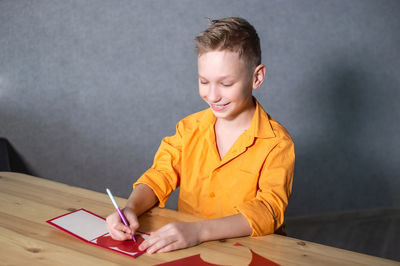 Cute boy cuts out a valentine's day card with hearts. a boy in a bright shirt