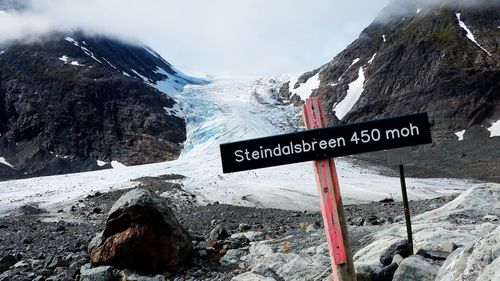 Information sign on snow covered mountain against sky