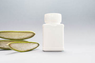 Close-up of pills in bottles against white background