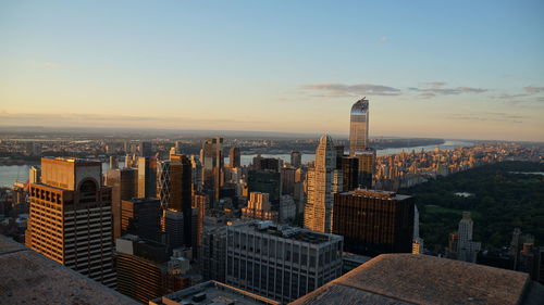 Modern buildings in city against sky during sunset