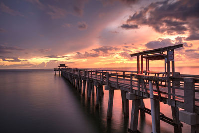 Pier over sea against sky during sunset