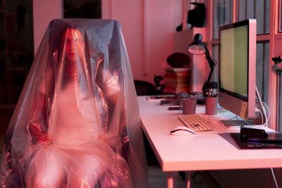 Young woman sitting on chair covered in plastic at home office during coronavirus crisis