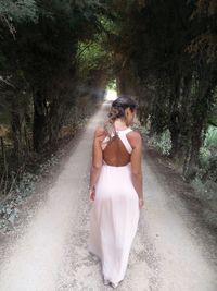 Rear view of woman with umbrella walking on road