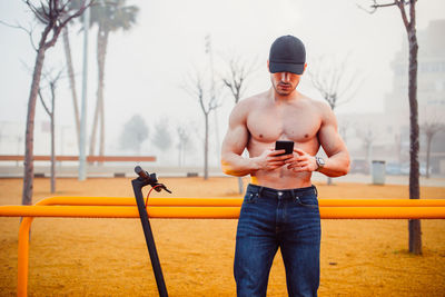 Fitness man using the mobile next to his electric scooter