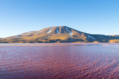 Scenic view of sea and mountains against clear blue sky