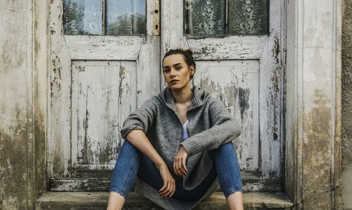 Portrait of woman sitting against door