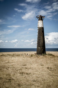 Bird on wooden post in sea against sky