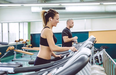 Side view of people walking on treadmills in gym