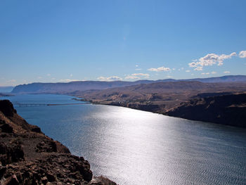 Scenic view of sea and mountains against blue sky