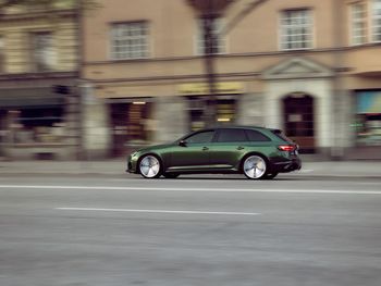 Side view of car on road against buildings