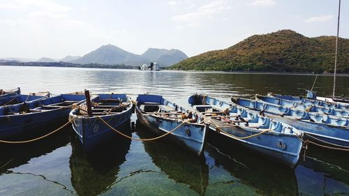 Sailboats moored in sea against sky