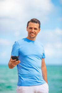 Portrait of young man standing at beach