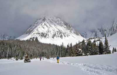 Panoramic view of people skiing on snow covered mountain against sky