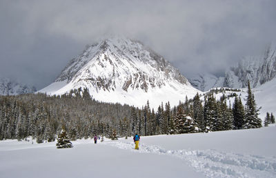 Panoramic view of people skiing on snow covered mountain against sky