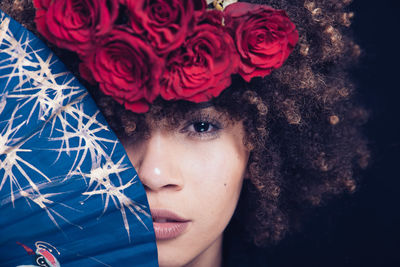 Close-up portrait of young woman with red rose