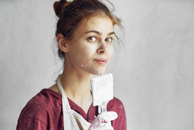 Portrait of young woman standing against wall