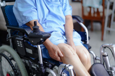 Midsection of woman with scar on knee sitting on wheelchair at hospital