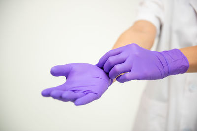 Close-up of hand holding purple flower over white background