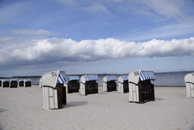 Hooded chairs on beach against sky