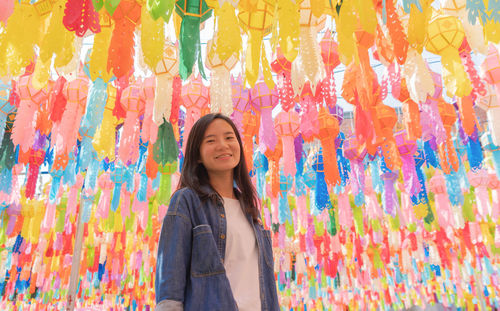 Smiling woman standing against multi colored paper lanterns