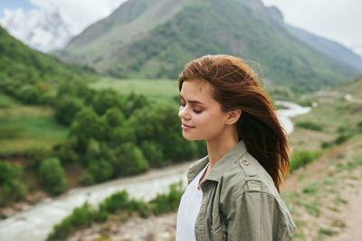 Young woman standing against mountain