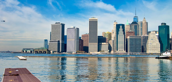 Sea by modern buildings against sky in city