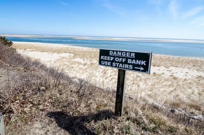 Information sign on beach against sky