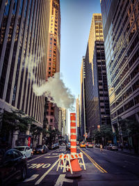 Chimney on road amidst buildings in city