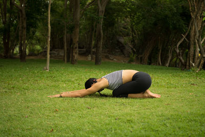 Woman practicing yoga on grassy field at public park