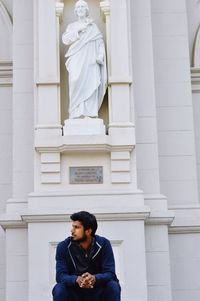 Young man sitting in front of a statue