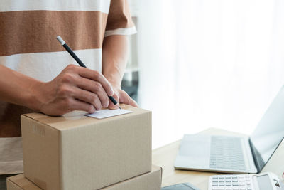 Midsection of man writing on parcel box