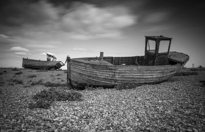 Abandoned boat at beach against sky