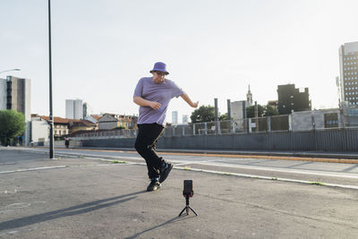 Teenage boy recording dancing video on smart phone at street