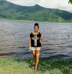 Full length portrait of young woman standing on shore
