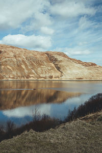 Scenic view of lake by mountain against sky