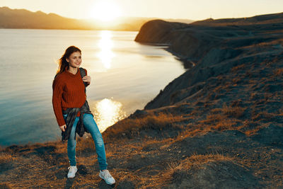 Portrait of man standing on rock against sky during sunset