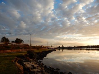 Scenic view of lake against cloudy sky at sunset