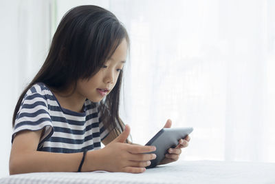 Close-up of girl using digital tablet in bedroom