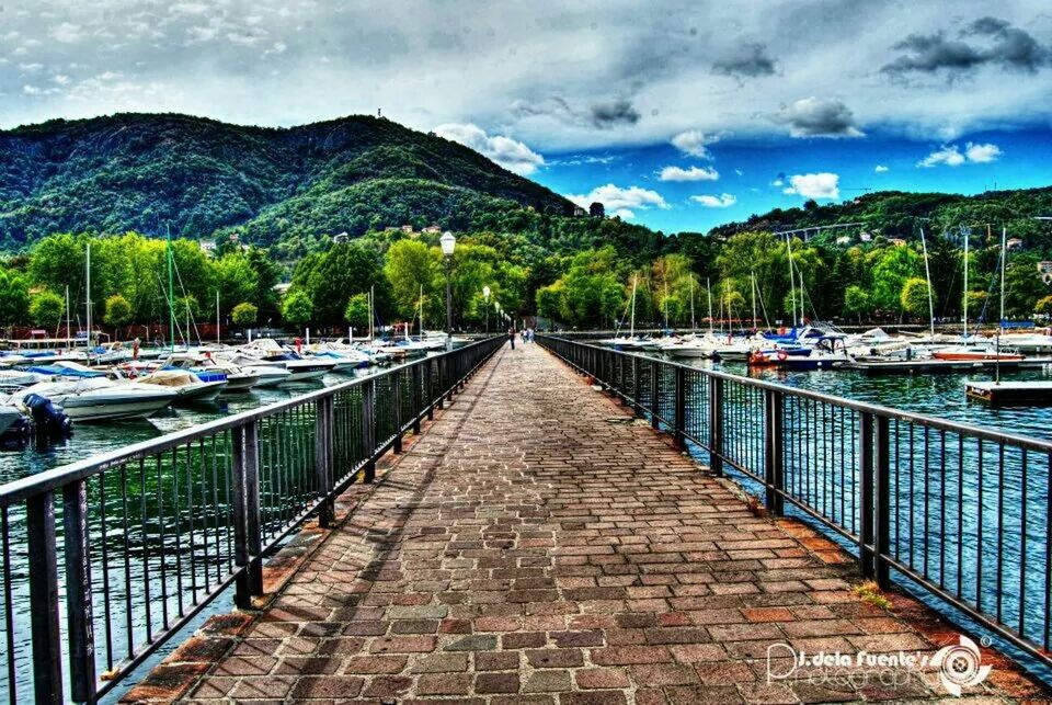 sky, mountain, the way forward, cloud - sky, railing, tree, diminishing perspective, transportation, water, cloudy, vanishing point, cloud, built structure, mountain range, nature, footpath, road, street light, scenics, leading