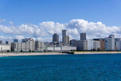 Sea by buildings against blue sky