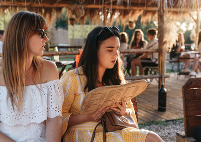 Two women looking at menu, ordering drinks in beach bar