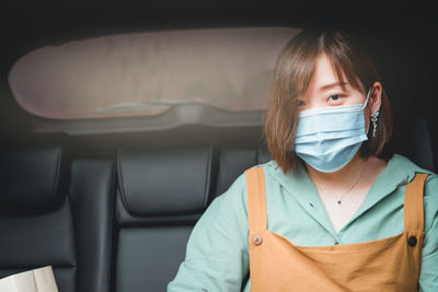 Portrait of woman wearing mask sitting in car